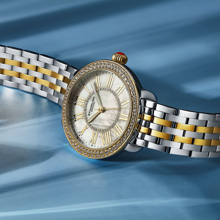 Luxury watch with silver and gold band on a blue fabric background