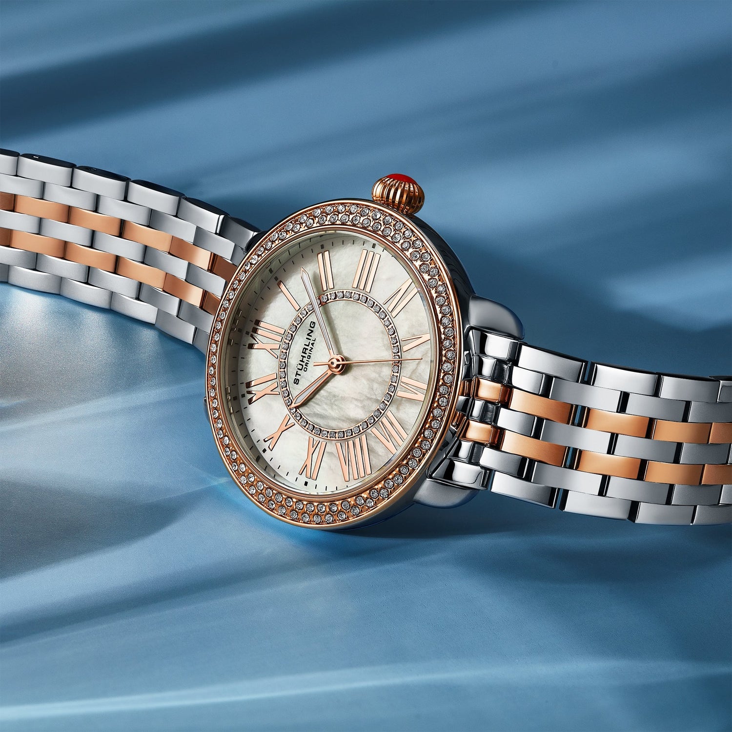 Luxury watch with silver and rose gold band on a blue background