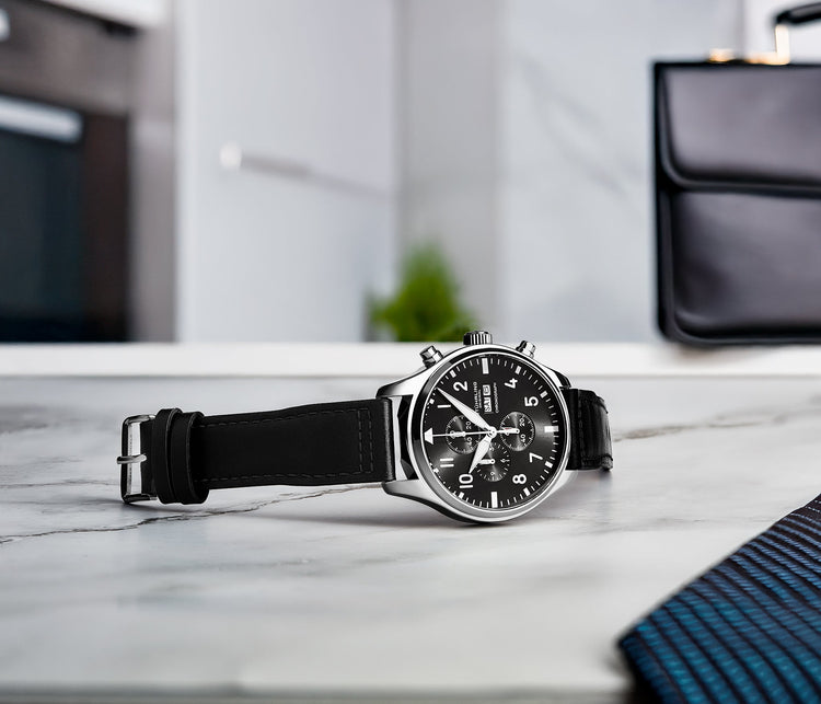 Black wristwatch with a detailed face on a marble surface, blurred background