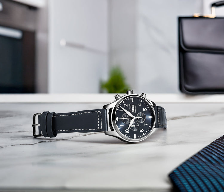 Black wristwatch with leather strap on a marble surface