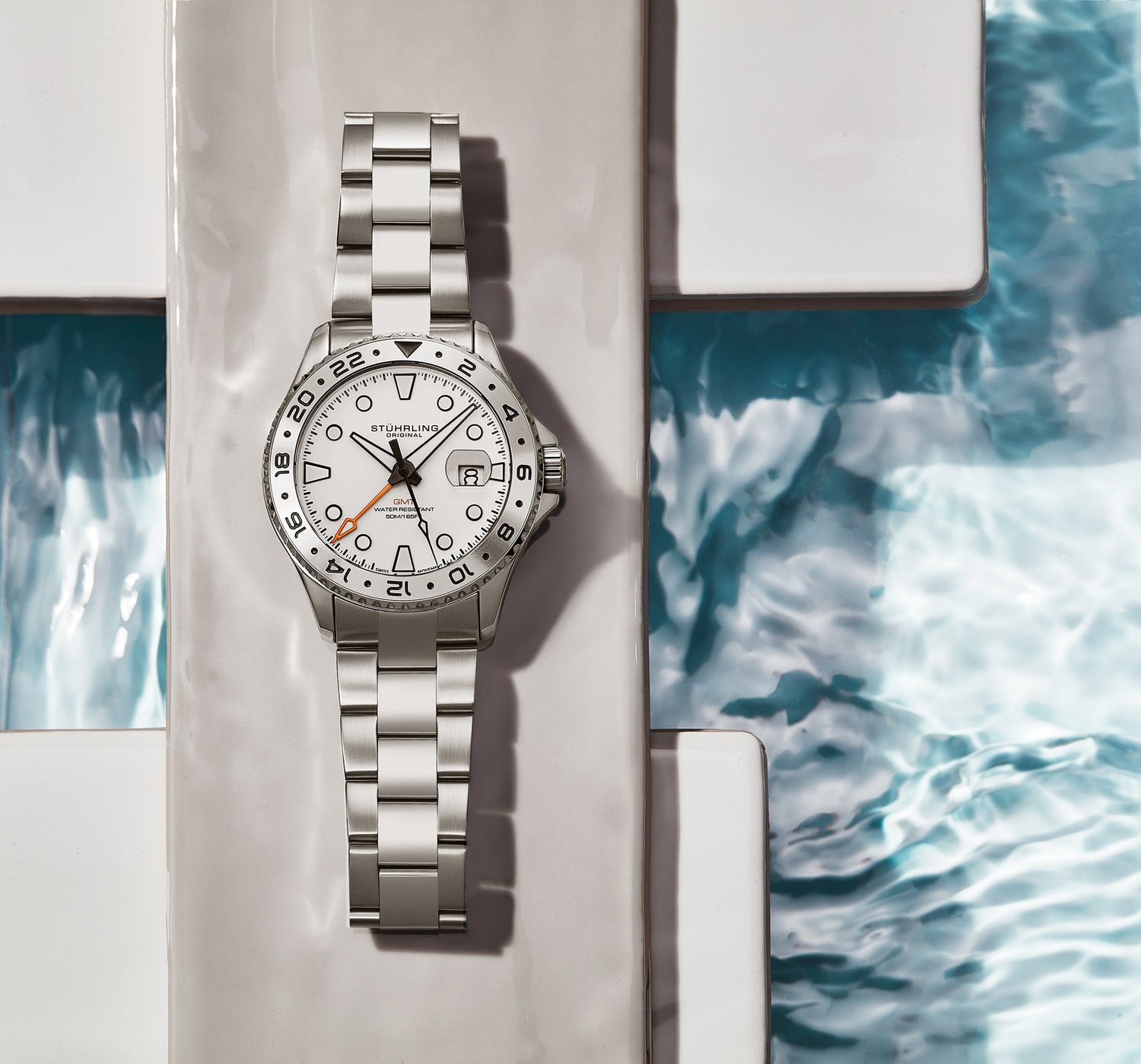 Silver watch with a white face on a marble surface with water pattern