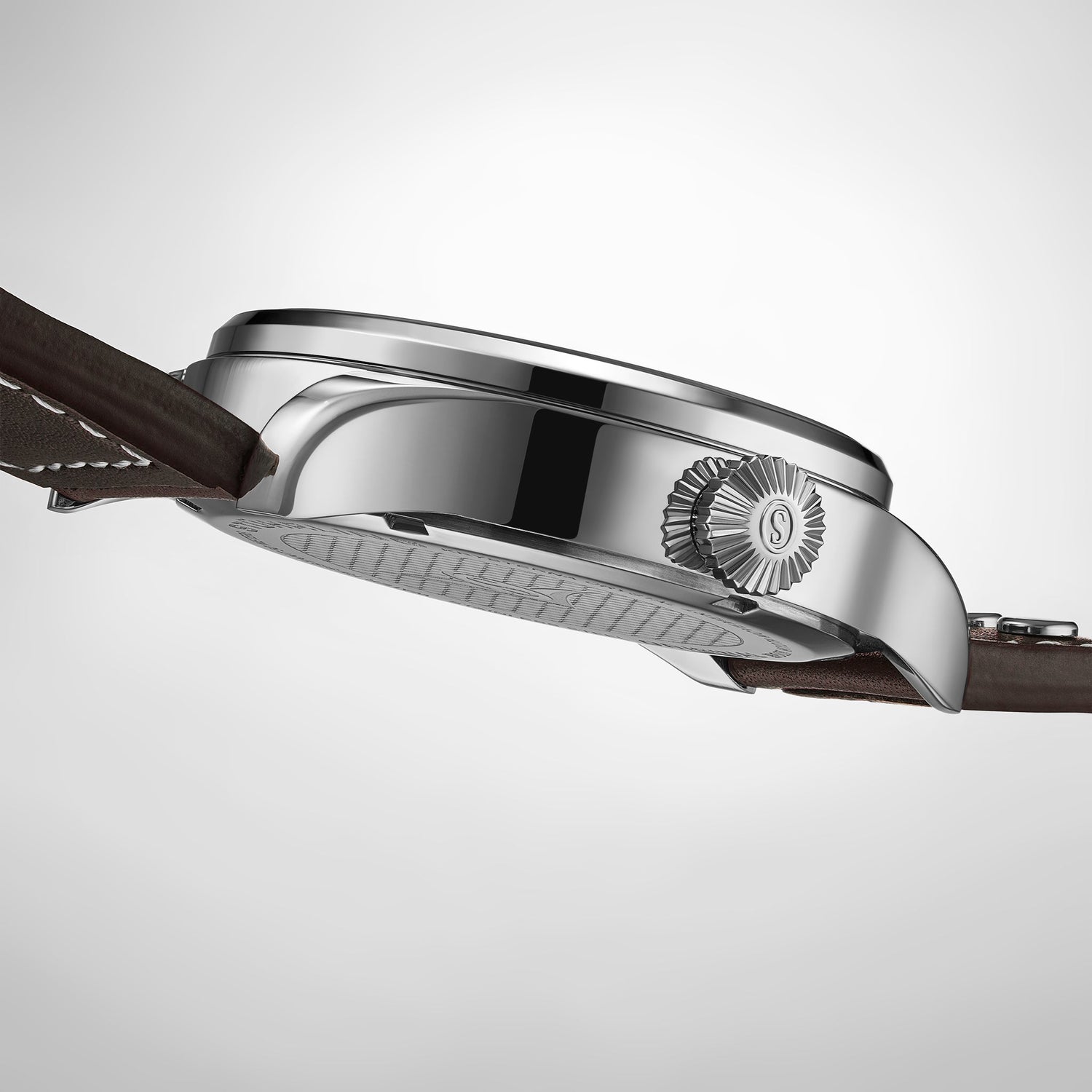 Close-up of a silver watch with a brown leather strap on a light gray background