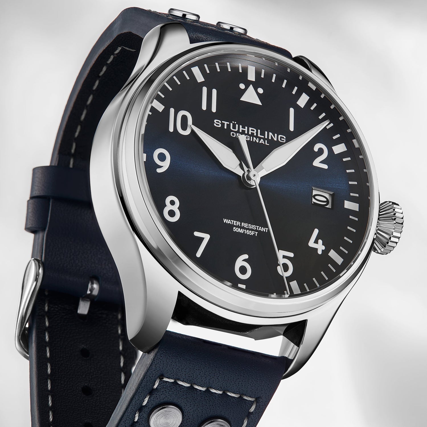 Stuhrling watch with black leather strap and blue dial on a light gray background