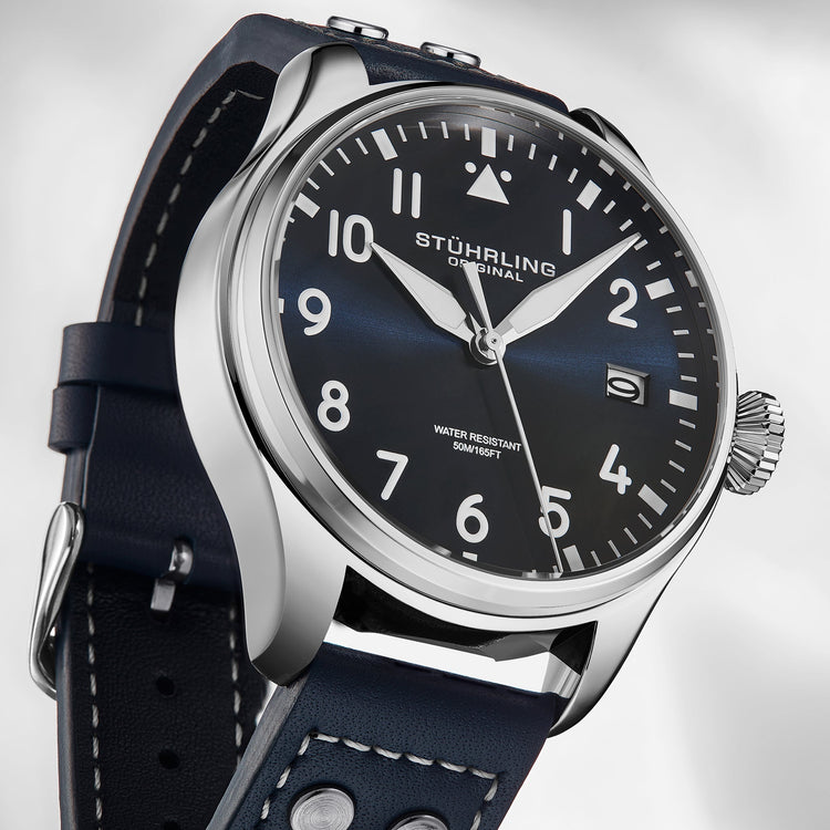 Stuhrling watch with black leather strap and blue dial on a light gray background