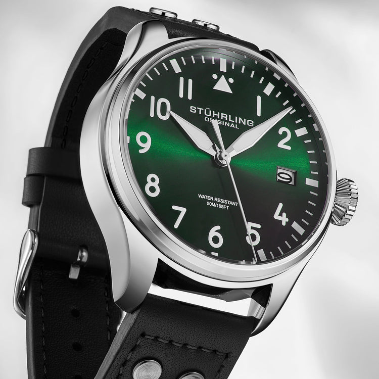 Stuhrling watch with green face and black strap on a light gray background