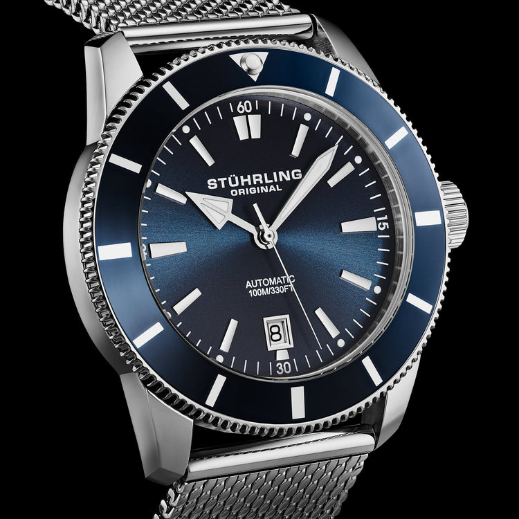 Stuhrling watch with blue dial and silver mesh band on a black background