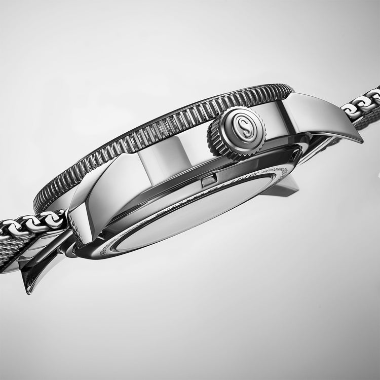 Close-up of a silver watch with detailed design on a light gray background