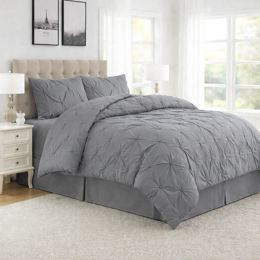 Gray comforter set on a bed in a bedroom with light-colored walls and furniture.