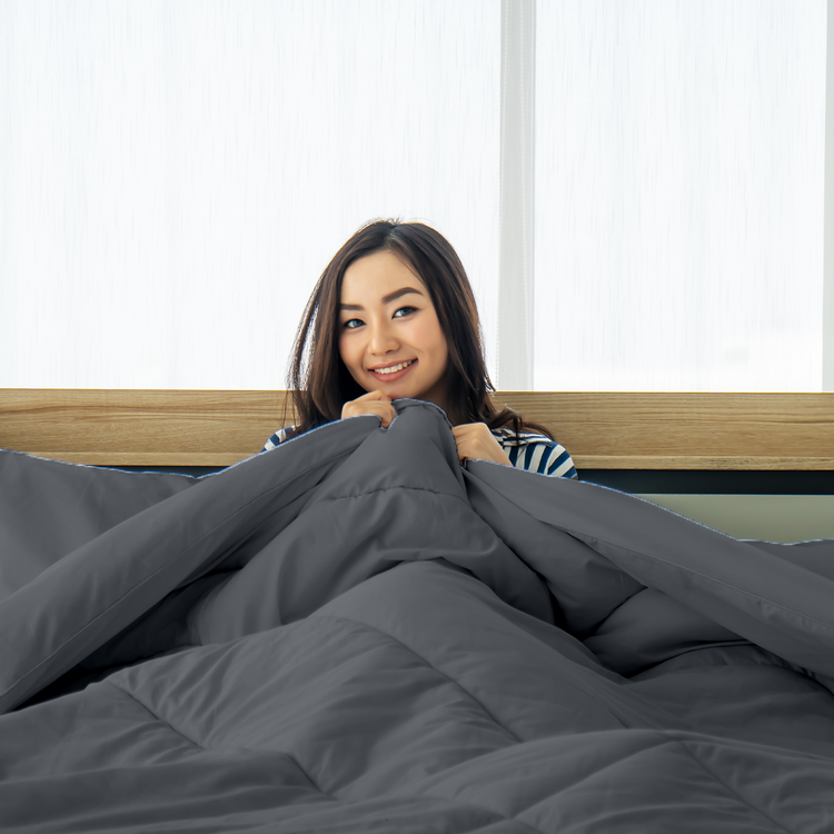 Woman peeking out from under sharkskin bedding in a bedroom setting