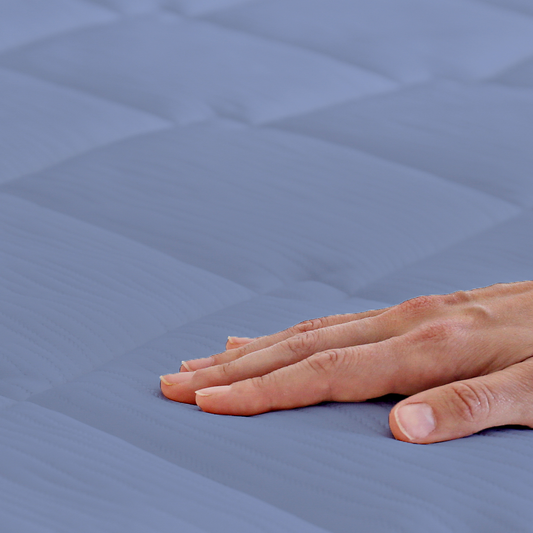 Woman peeking out from under a blue comforter in a bedroom setting