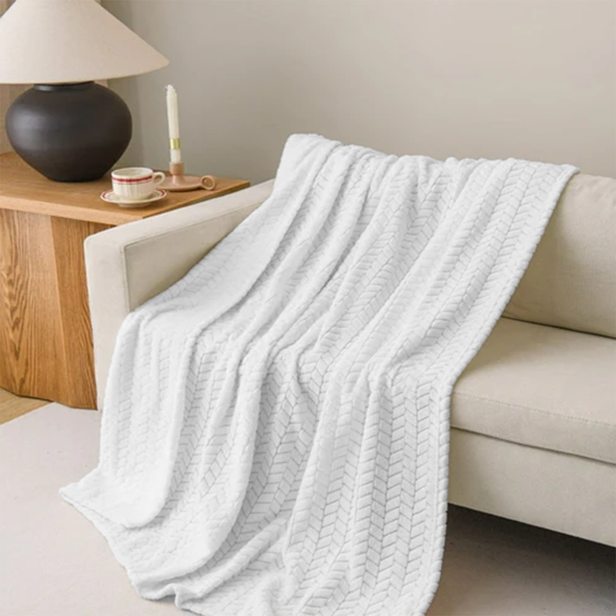 Light gray textured throw blanket draped over a beige sofa in a living room setting.