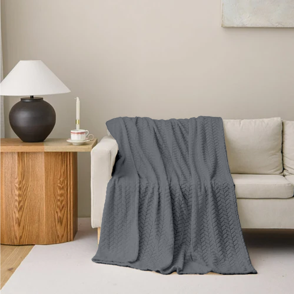 Gray textured blanket draped over a beige sofa in a living room setting.