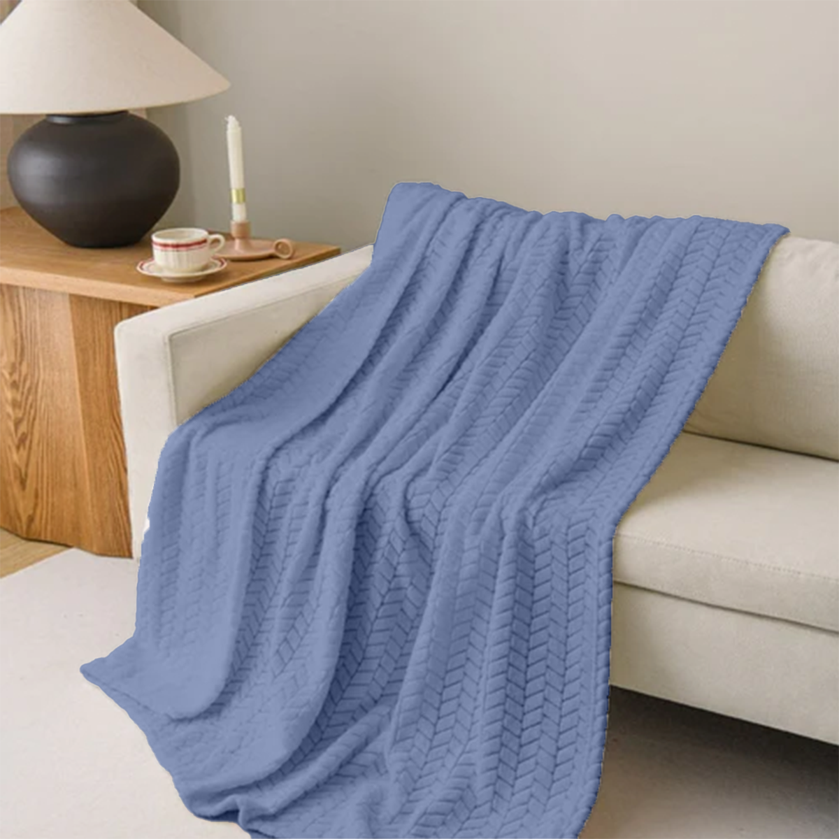 Blue knitted blanket draped over a sofa in a cozy living room setting.