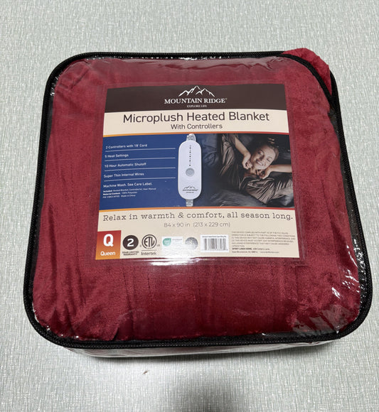 Red electric blanket draped over a white couch with power cord visible.