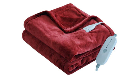 Red electric blanket draped over a white couch with power cord visible.