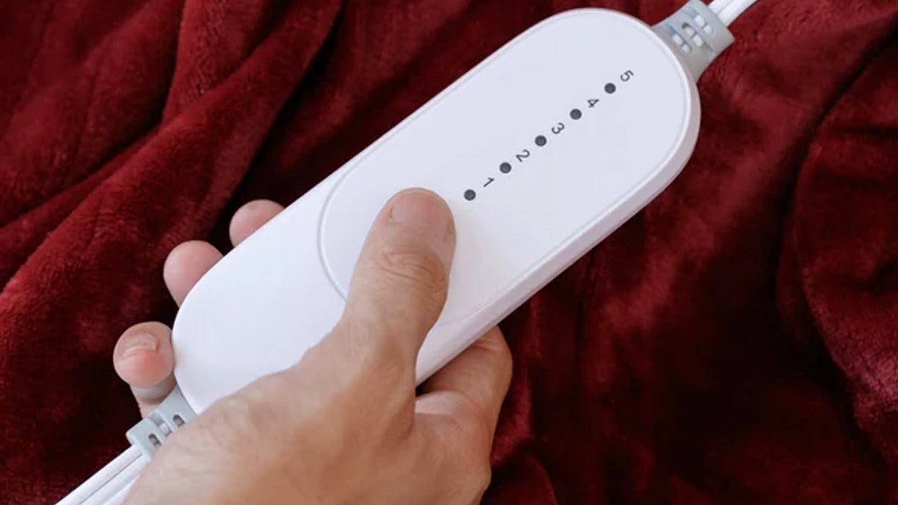 Hand holding a white electronic device against a red fabric background