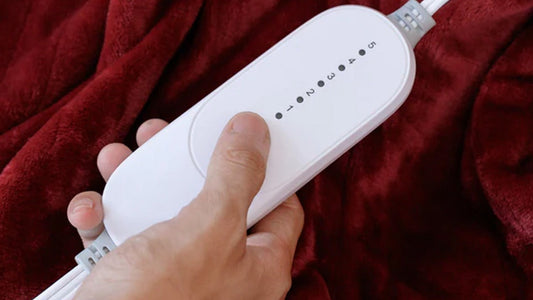 Red electric blanket draped over a white couch with power cord visible.