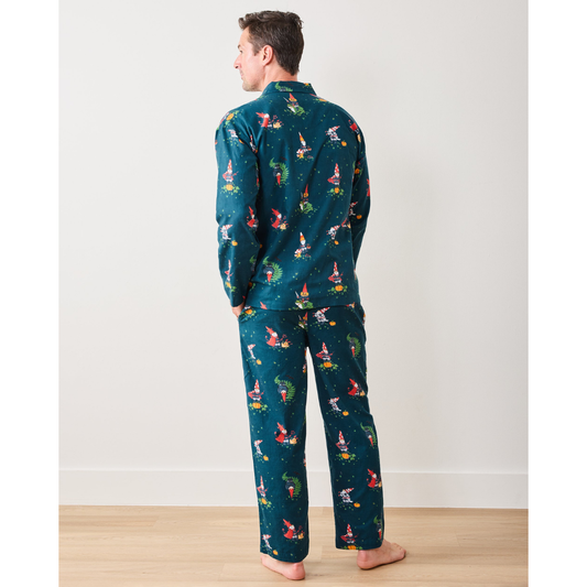Man wearing a festive teal pajama set with colorful patterns, sitting on a wooden floor.