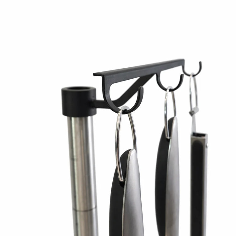 Set of kitchen utensils hanging on a magnetic strip against a white background