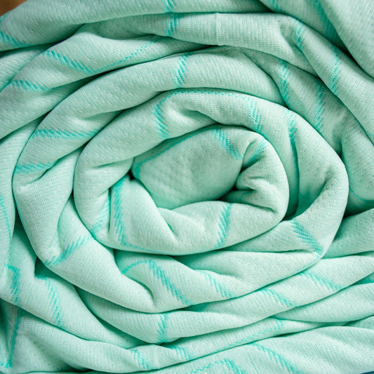 Teal quilted bedspread and pillowcases on a bed in a bedroom setting.