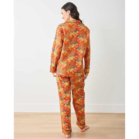 Woman wearing a patterned orange pajama set against a plain background