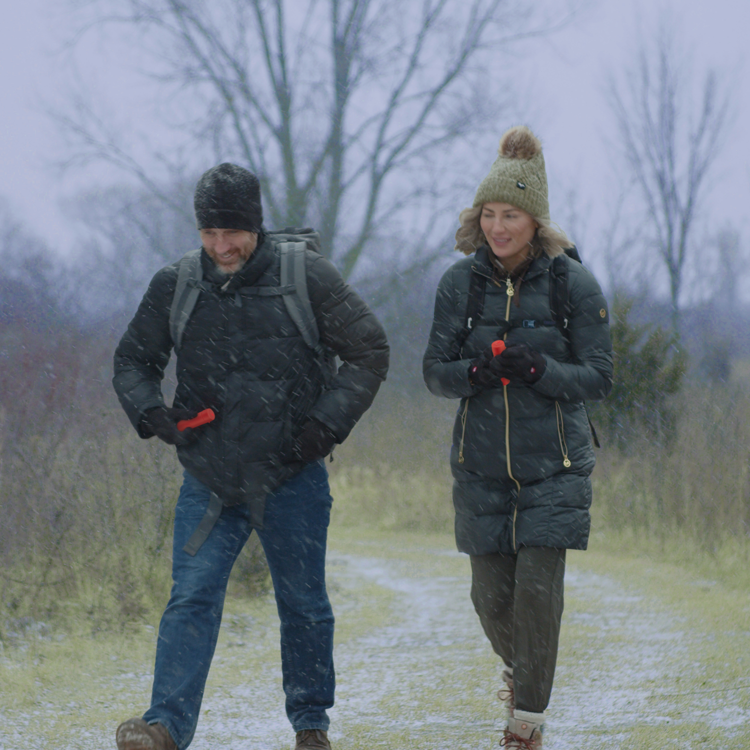Two people walking on a snowy path in a foggy landscape