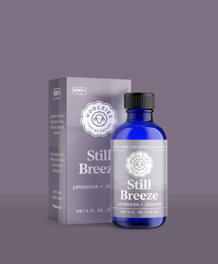 Blue bottle and box of 'Still Breeze' essential oil on a gray background