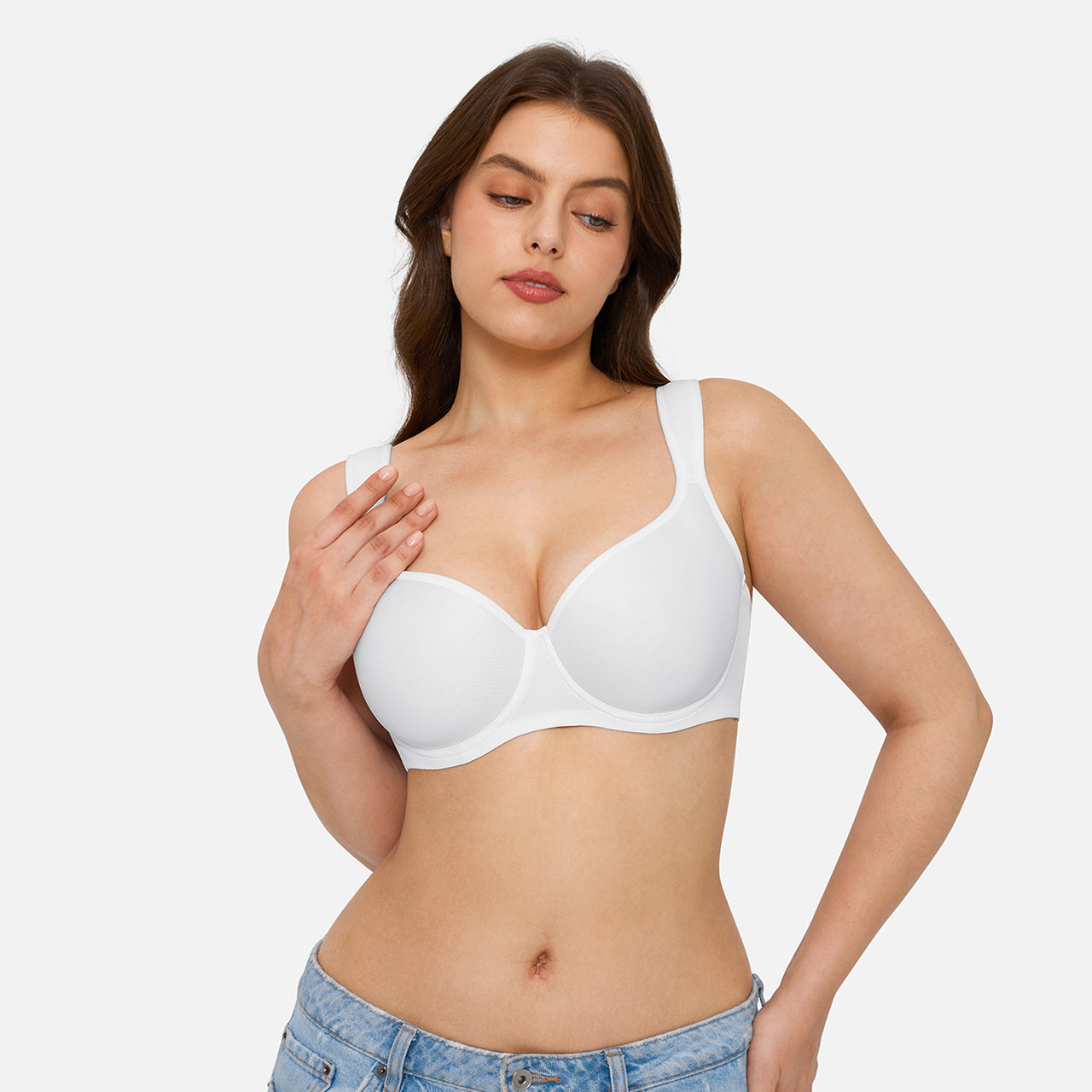 A woman modeling a white seamless underwire bra against a light gray studio background.