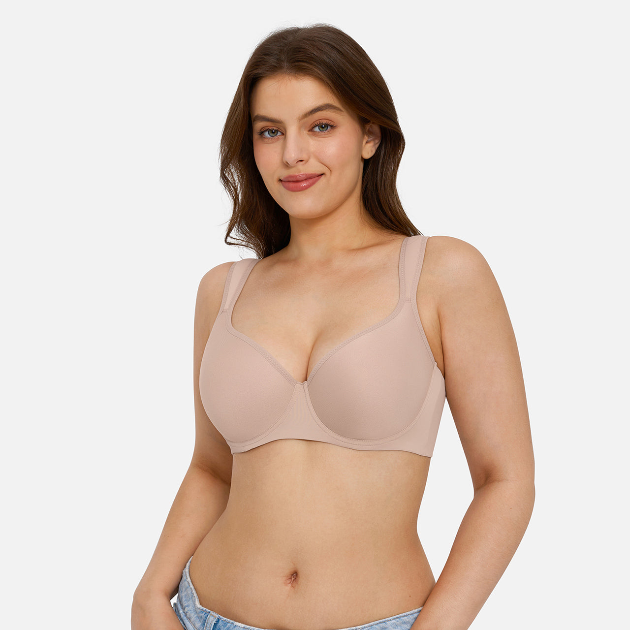 A woman modeling a seamless, wireless, underwire bra in a light beige color, shown from the waist up against a solid light gray background.
