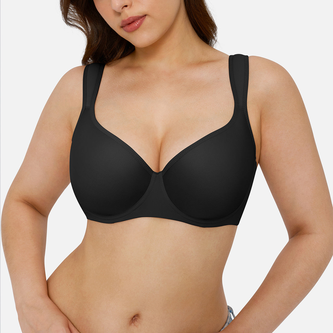 A woman wearing a black wireless underwire bra against a light gray studio background.