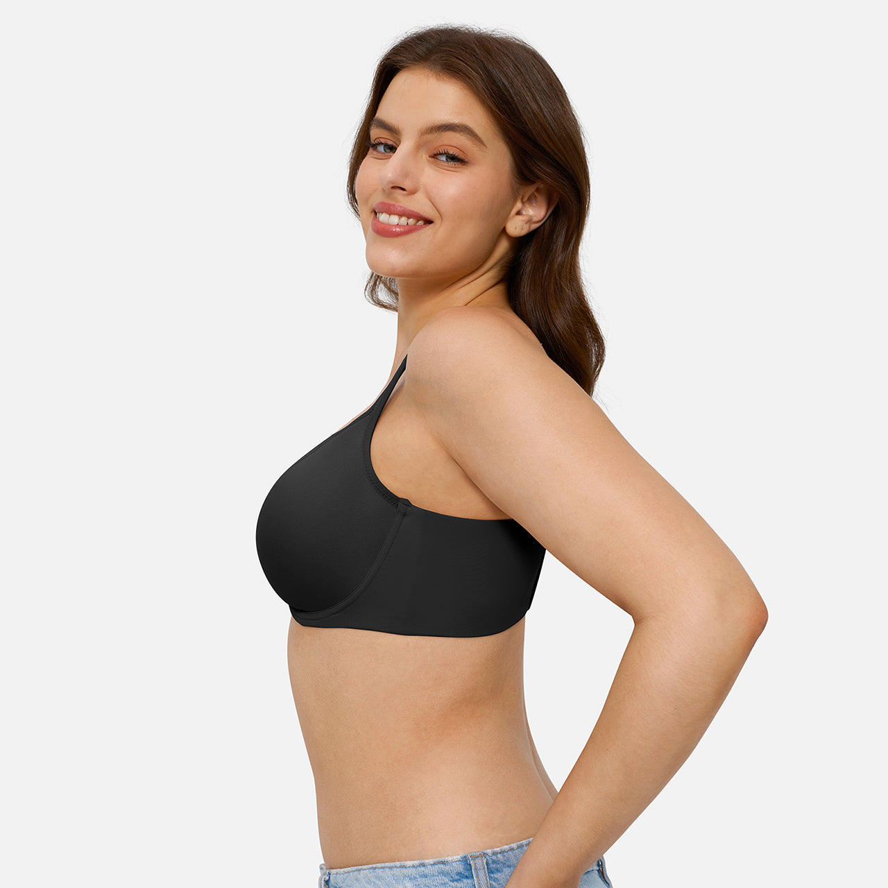 A woman wearing a black one-shoulder sports bra, shown from a side-back angle against a light gray studio background.