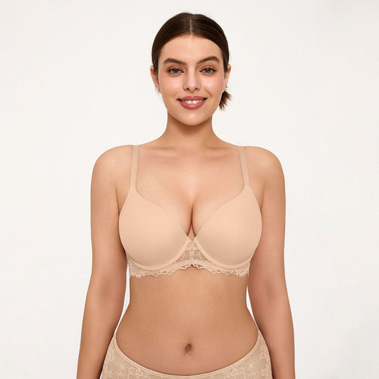 A woman modeling a light beige underwire bra with scalloped lace trim, shown against a plain light background.