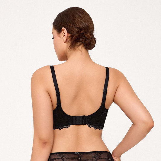 A woman modeling a black underwire bra with lace trim, styled with an open white shirt against a plain light background.