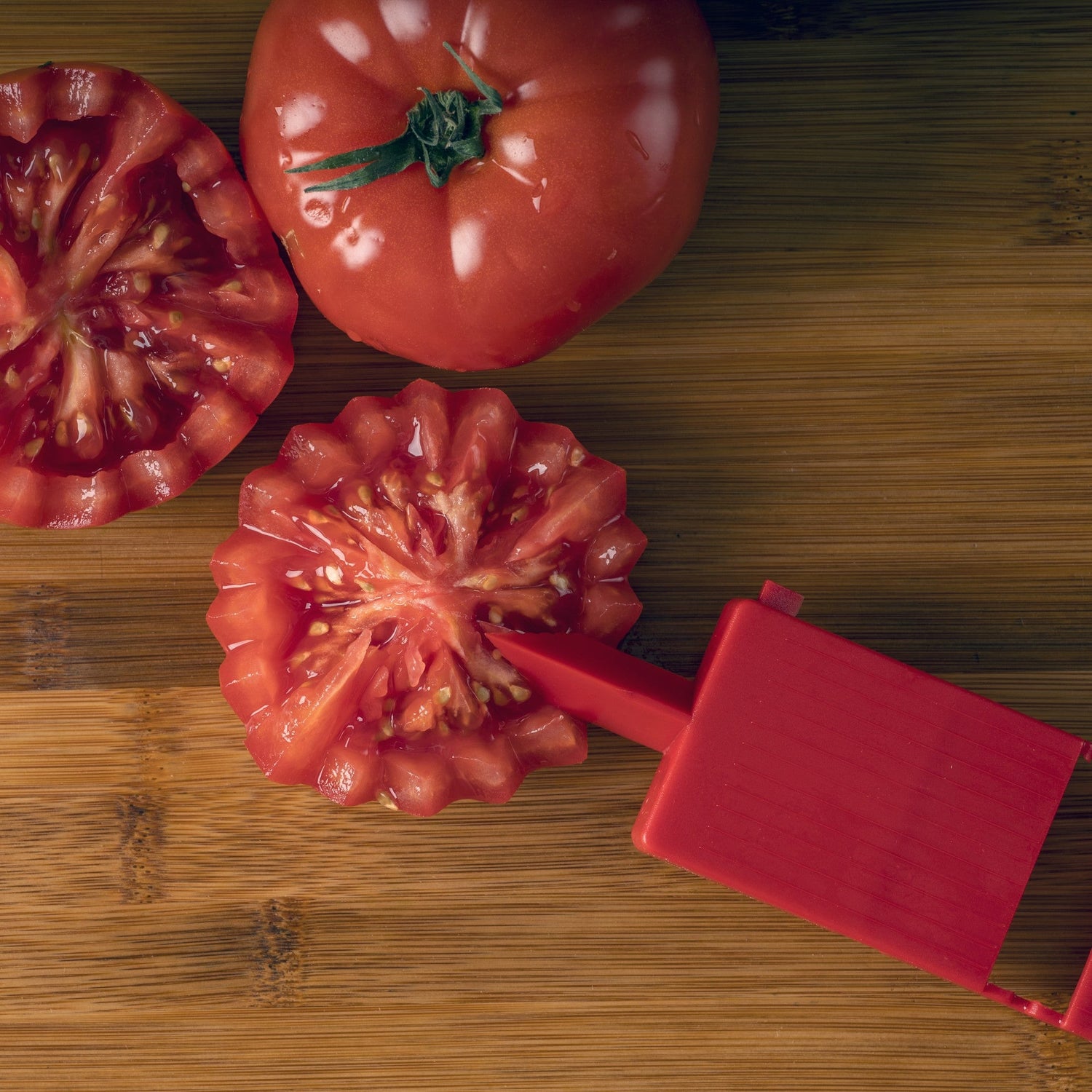 Tomatoes and a tomato slicer on a wooden surface