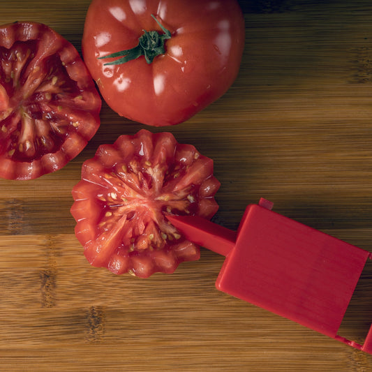 Set of kitchen tools including a peeler, mandoline, and other cutting tools with sliced vegetables on a white background.