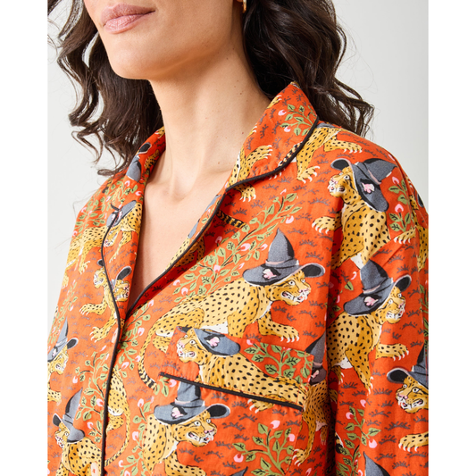 Woman wearing a patterned orange pajama set against a plain background