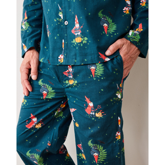 Man wearing a festive teal pajama set with colorful patterns, sitting on a wooden floor.
