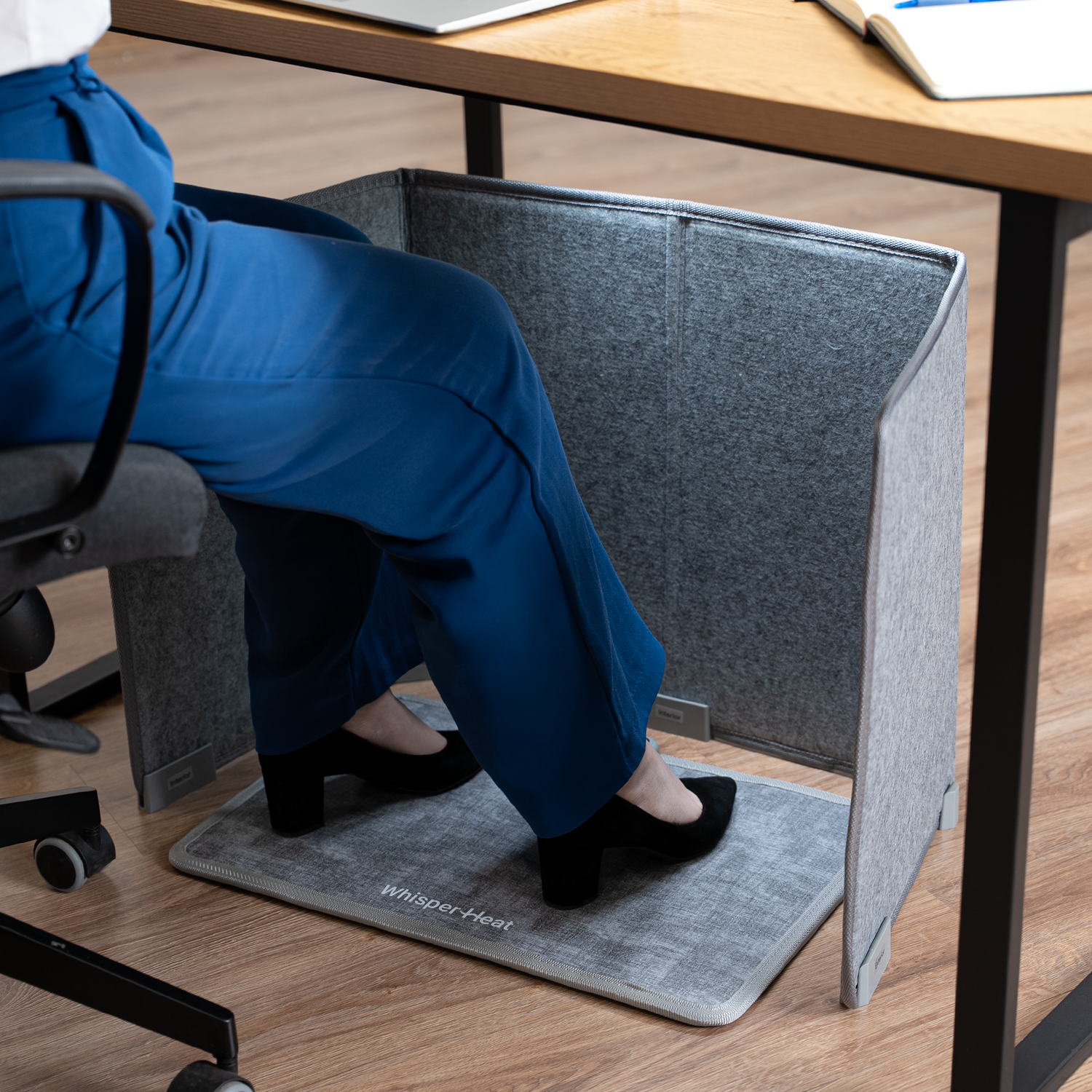 Person sitting at a desk with a gray office mat on the floor.