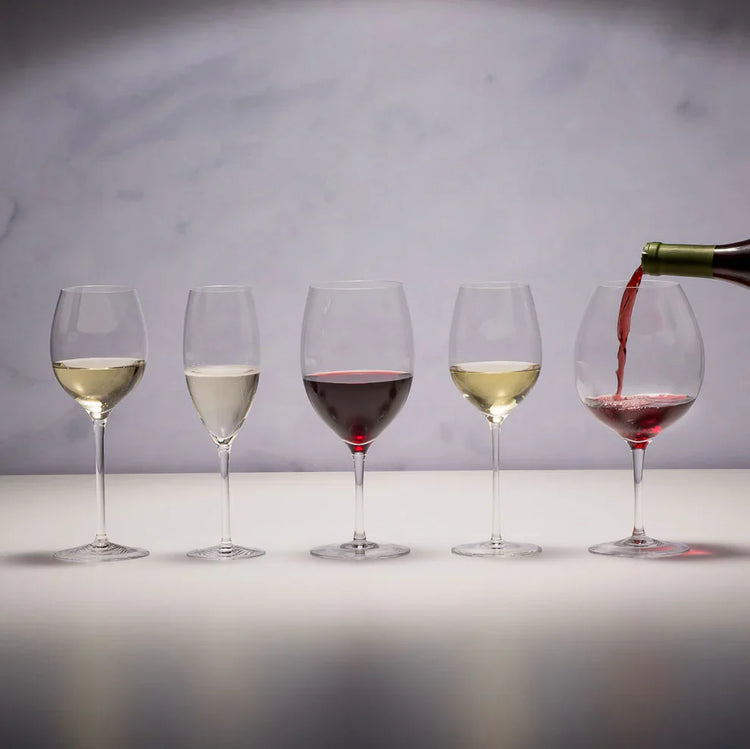 Five wine glasses with different types of wine on a neutral background