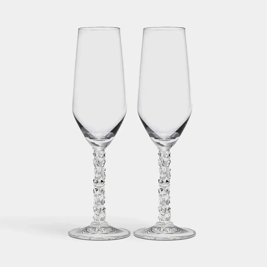Two clear glass champagne flutes with intricate designs on a white background