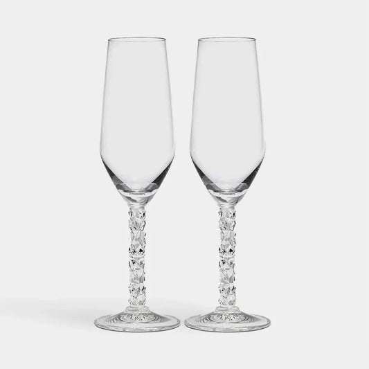 Two clear glass champagne flutes with intricate designs on a white background