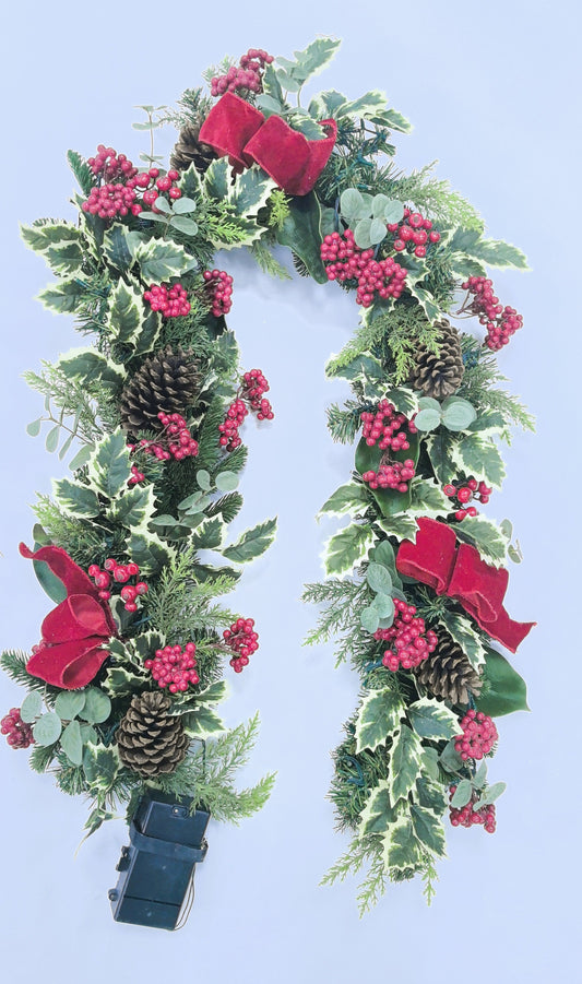 Decorative wreath with greenery, red berries, and pinecones on a white background