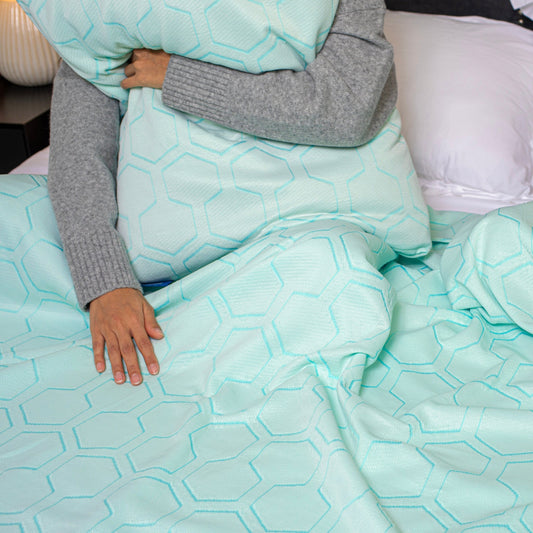 Teal quilted bedspread and pillowcases on a bed in a bedroom setting.