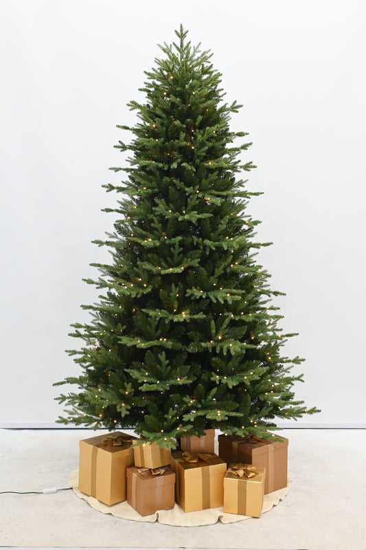 Decorated Christmas tree with lights in a room with a fireplace and gift boxes.
