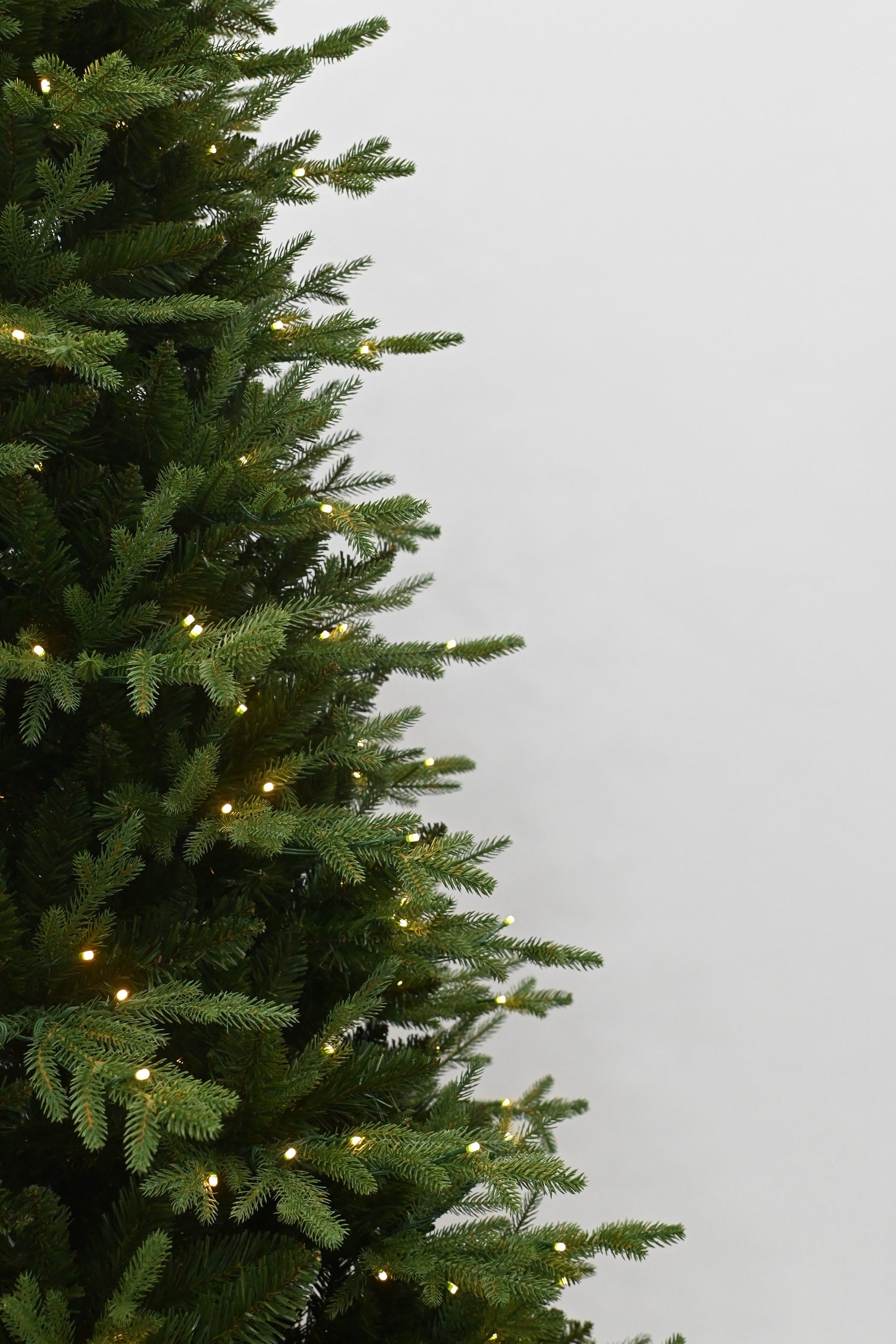 Decorative Christmas tree with lights on a plain background