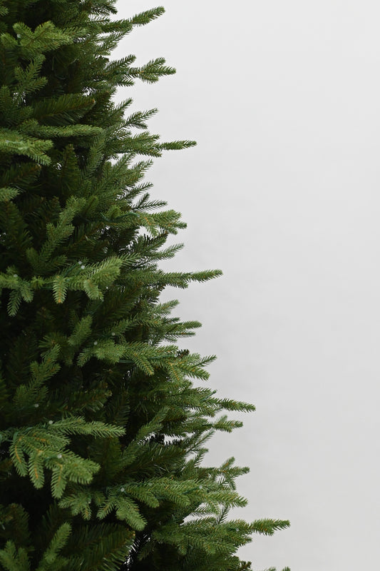 Decorated Christmas tree with lights in a room with a fireplace and gift boxes.