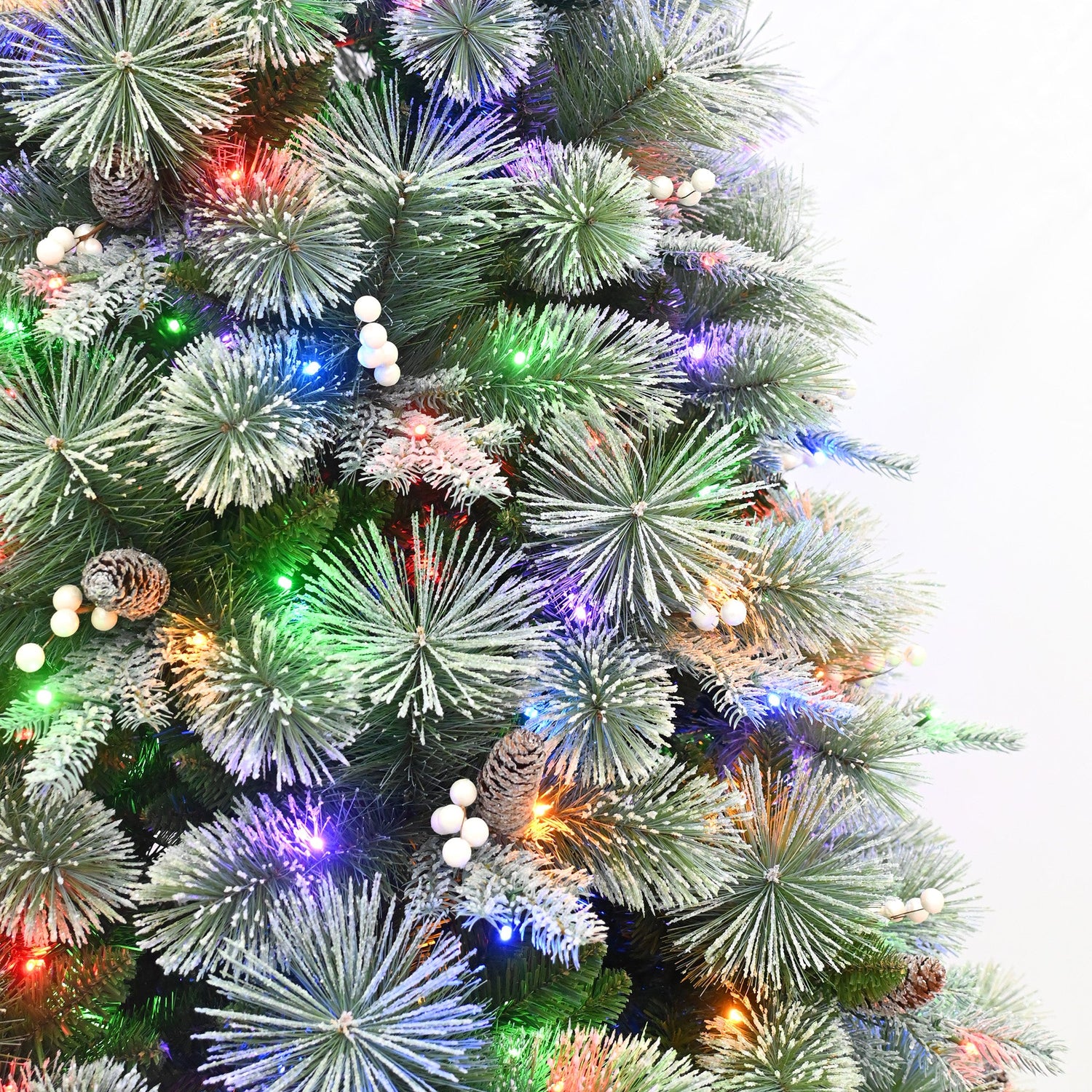Decorated Christmas tree with colorful lights and pinecones on a white background