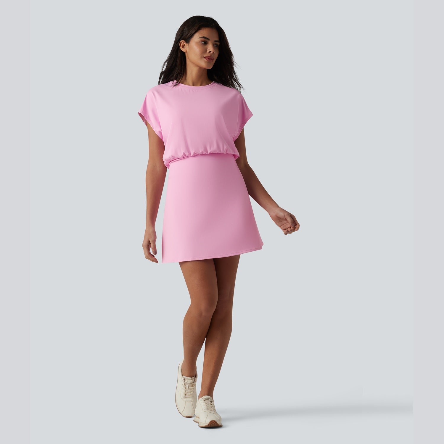 Woman wearing a pink dress on a plain background