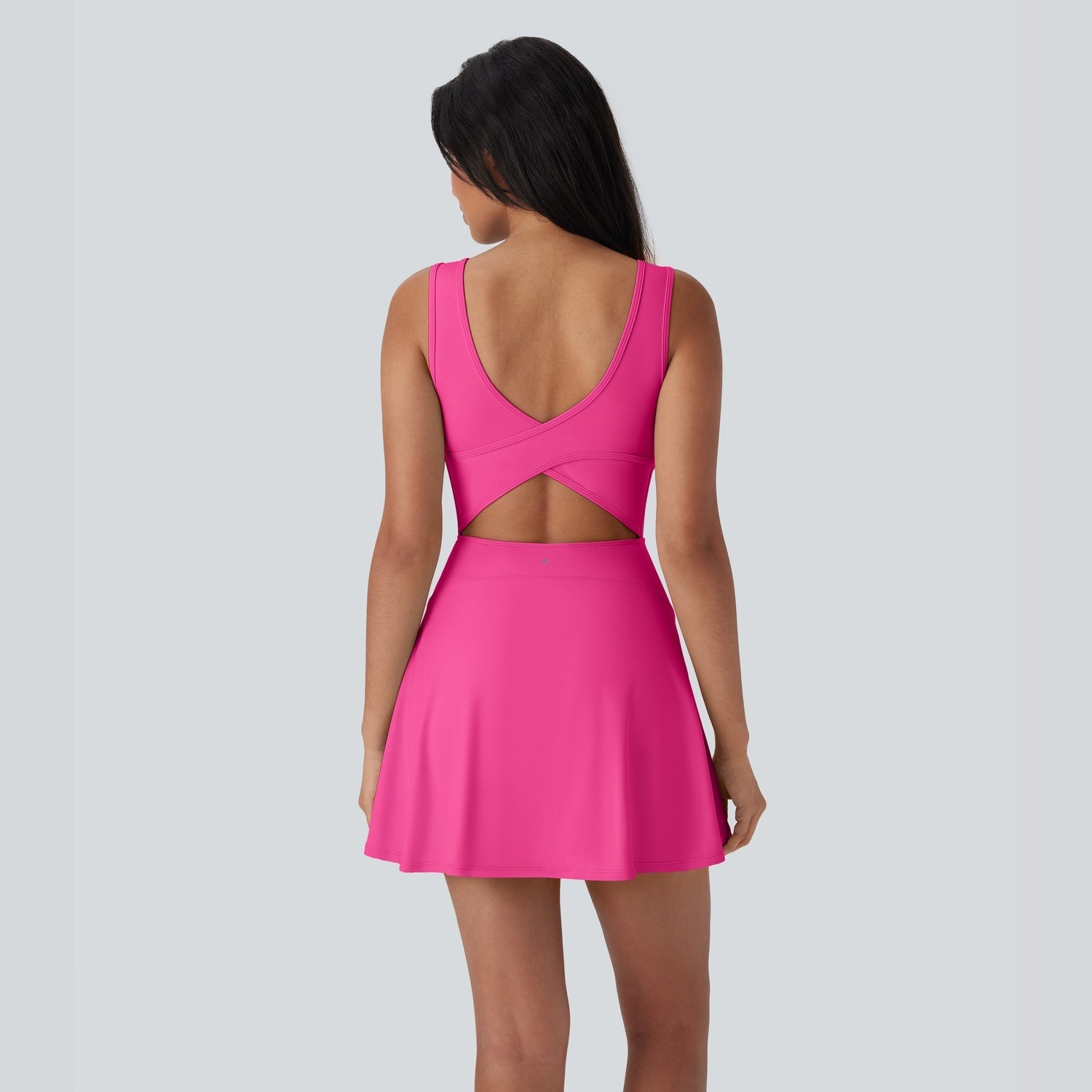 Pink dress with cut-out back on a model against a light gray background