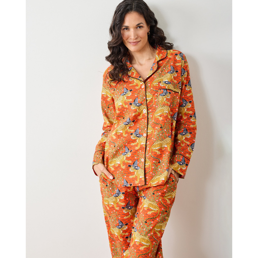 Woman wearing a patterned orange pajama set against a plain background